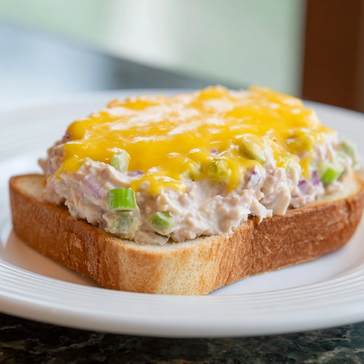 Golden, melty Classic Tuna Melt Sandwich with bubbly cheese and crispy, toasted bread served hot.
