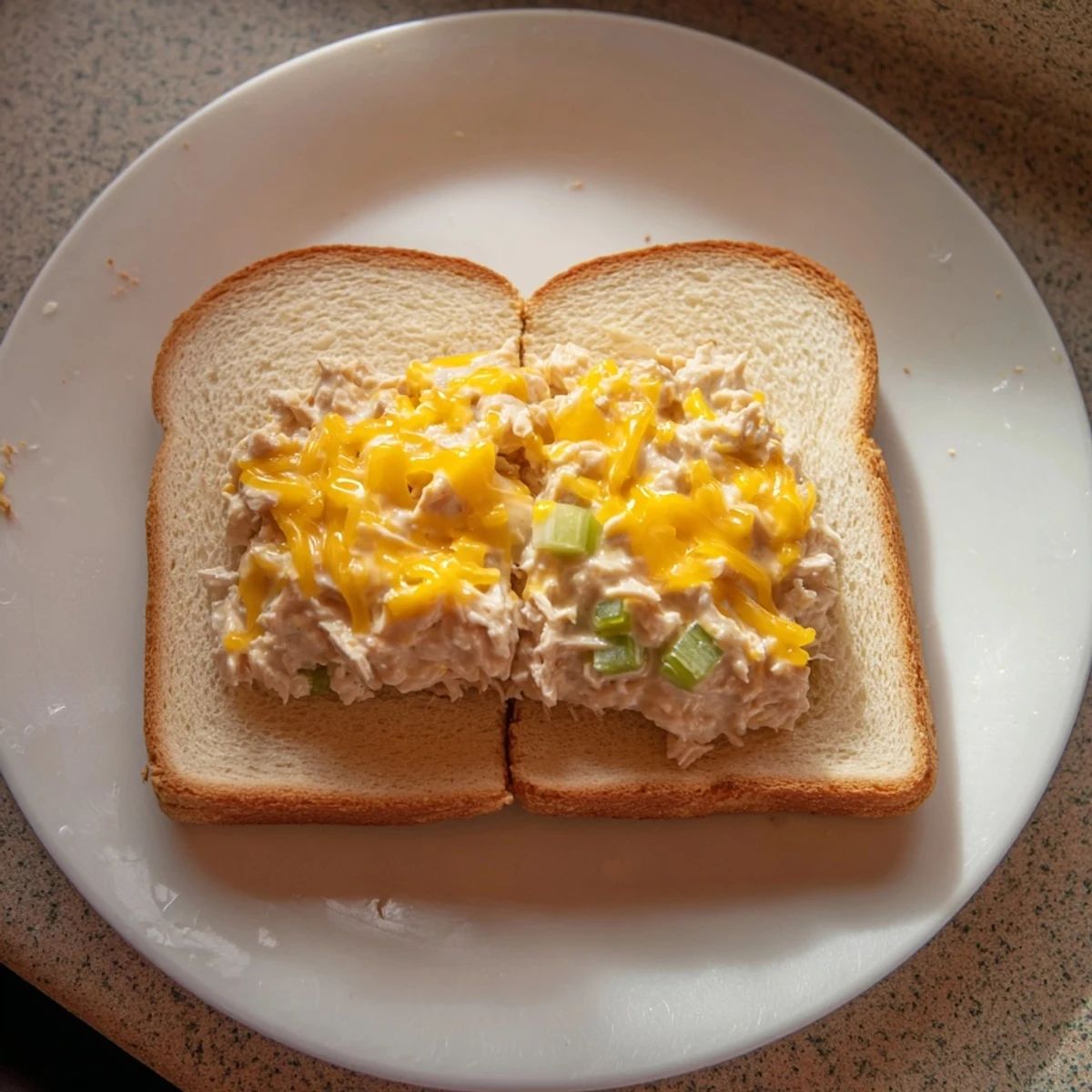 A close-up of a perfectly grilled Classic Tuna Melt Sandwich, oozing with creamy tuna and melted cheese.