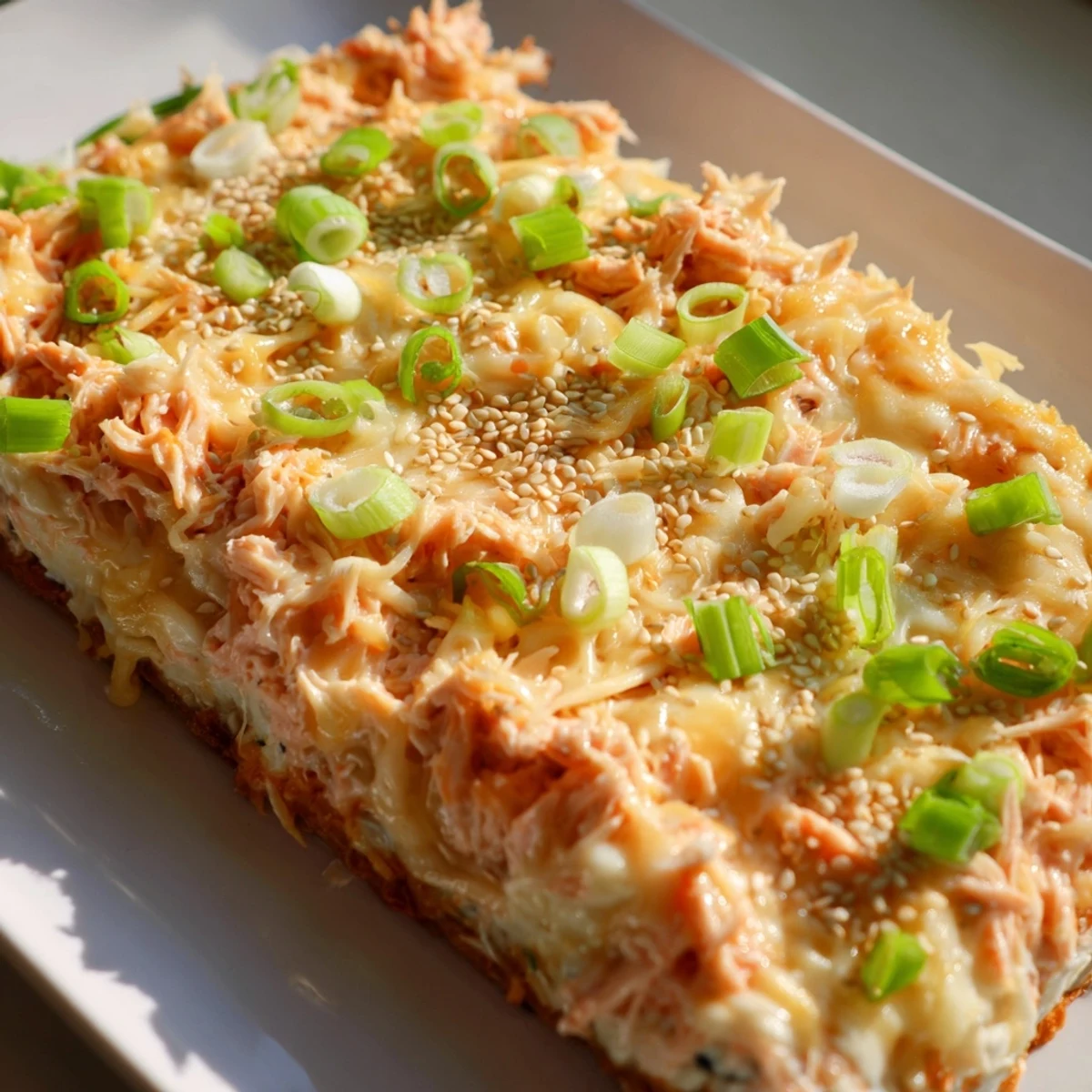 Creamy Salmon Sushi Bake topped with melted cheese, sesame seeds, and green onions.