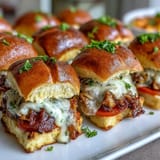 Hot Brown sliders on brioche buns with turkey, bacon, and creamy Mornay sauce, baked golden and topped with Parmesan.