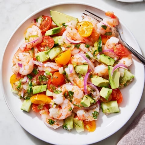 Bright and colorful, this image showcases a chilled bowl of fresh shrimp ceviche with lime wedges.