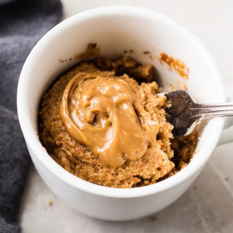Fluffy 2-Minute Peanut Butter Mug Cake, warm and freshly microwaved, ready to eat with a spoon.