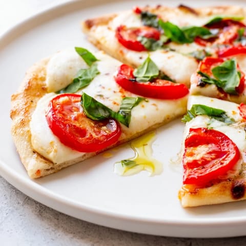 Golden-brown Quick Margherita Naan Pizza, featuring bubbly cheese and a fragrant basil garnish.