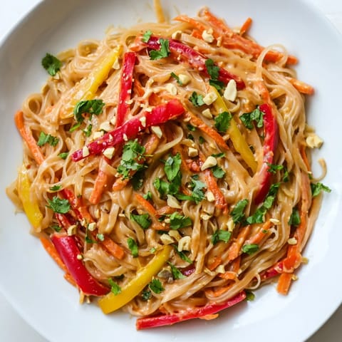 Close-up of freshly prepared Spicy Peanut Noodles, coated in a rich, glossy peanut sauce.