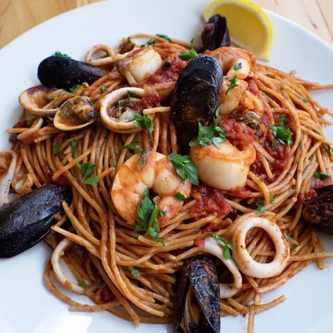 A close-up of Seafood Marinara Pasta: tender pasta coated in a vibrant, seafood-packed sauce.