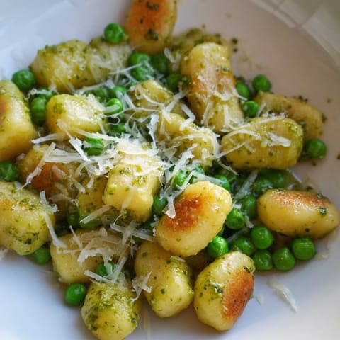 A close-up of Pesto Pea Gnocchi Skillet with wilted spinach and melted Parmesan.  