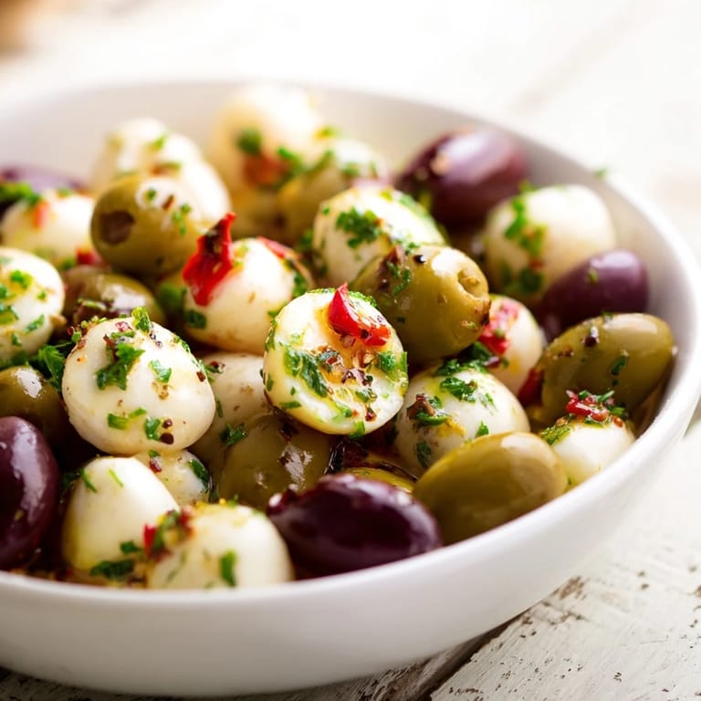 A delicious serving of The Cobblestone Courtyard, with varied olives nestled among golden crackers on a platter.