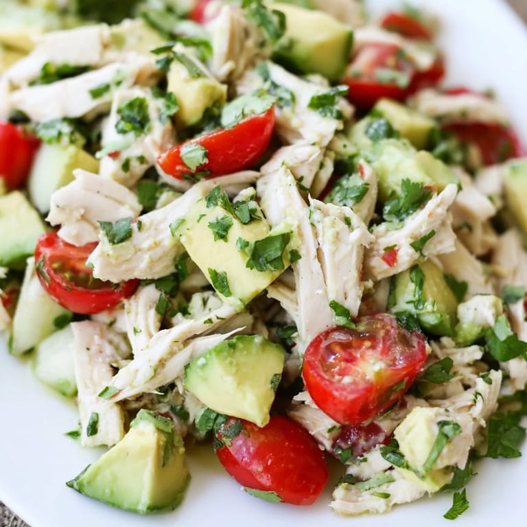 Fresh avocado chicken salad piled high on a plate, featuring juicy diced avocado, red onion, and herbs tossed with olive oil and lime.