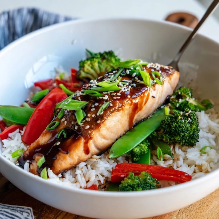 A close-up view of juicy, glazed salmon with vibrant steamed broccoli, snap peas, and red bell peppers for a healthy weeknight dinner.