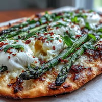 Roasted asparagus flatbread topped with creamy burrata cheese, bursting with lemon flavor.